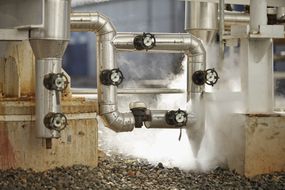 在工业环境中，蒸汽从管道中释放出来＂width=