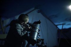 男孩在晚上用望远镜看