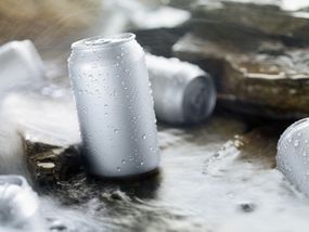 Silver cans with condensation drops, sitting in a stream of water