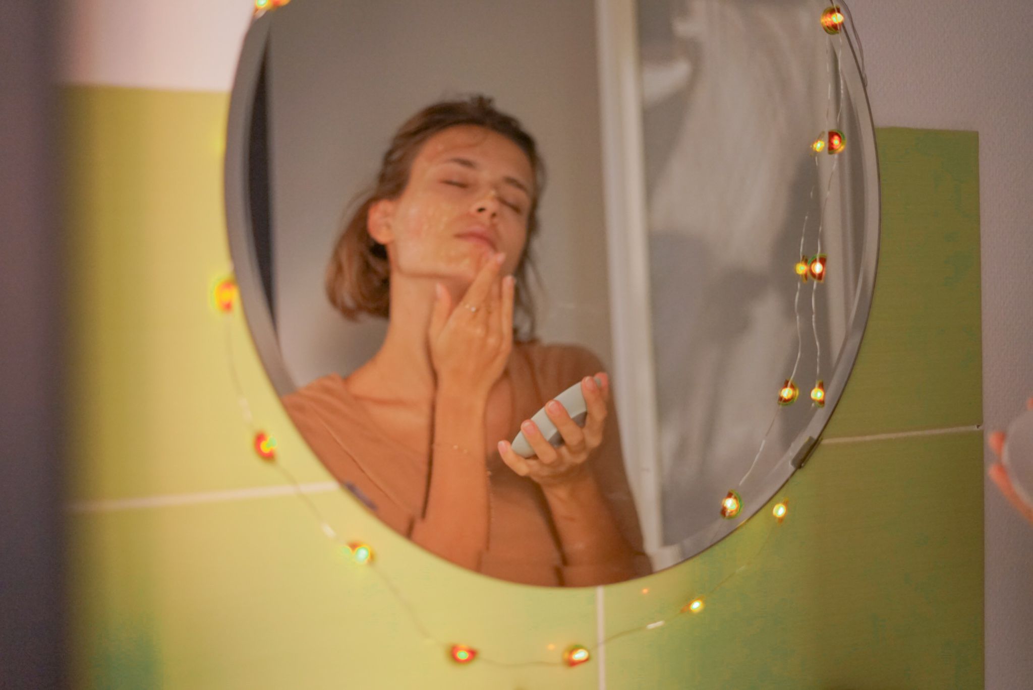 在妇女镜子的反射在卫生间摩擦蜂蜜的蜂蜜在面孔为自然秀丽治疗