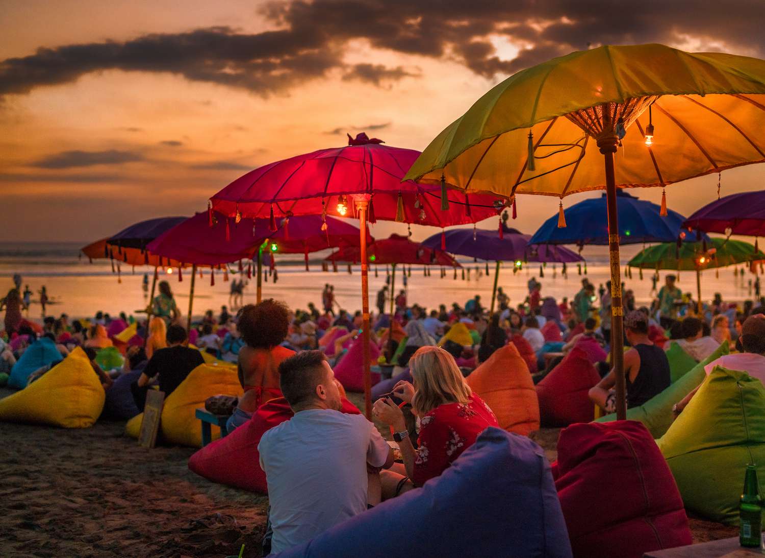 日落时分，数百名游客在巴厘岛的海滩上打着伞