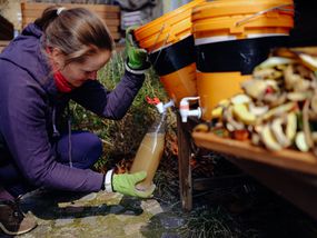Woman harvesting environmentally friendly fertilizer from bio waste using diy bokashi.