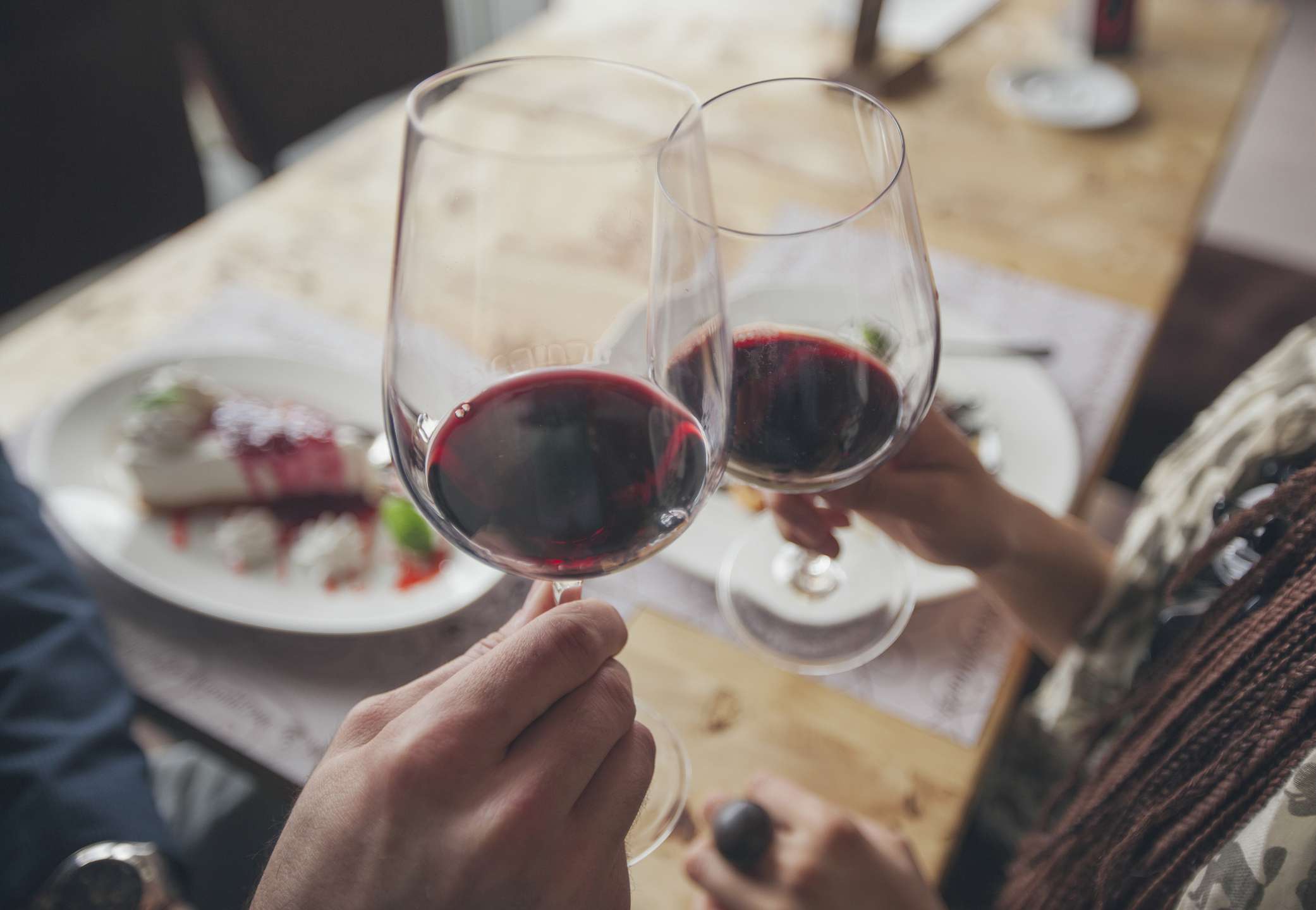 两个人用玻璃杯端着的红酒。