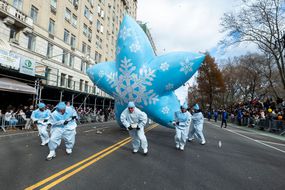 身穿白色西装的工作人员拉着大气球穿过梅西感恩节游行