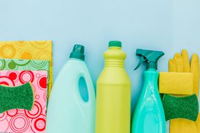 一排清洁用品，包括海绵，三个瓶子，和一个黄色橡胶手套＂width=