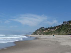 在蓝天下，沙滩与太平洋在丘陵的海岸线上相遇