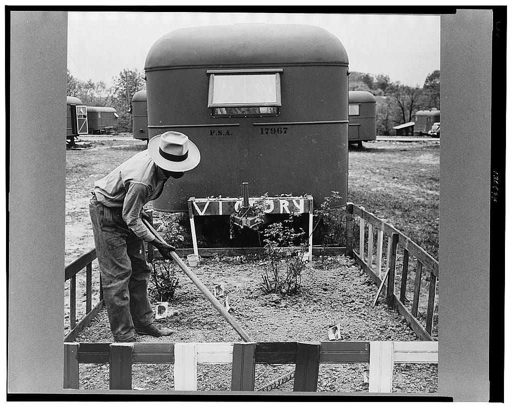 一个男人在拖车后面的小栅栏花园工作