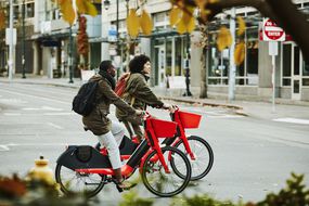 一对夫妇在大城市里骑着租来的红色电动自行车