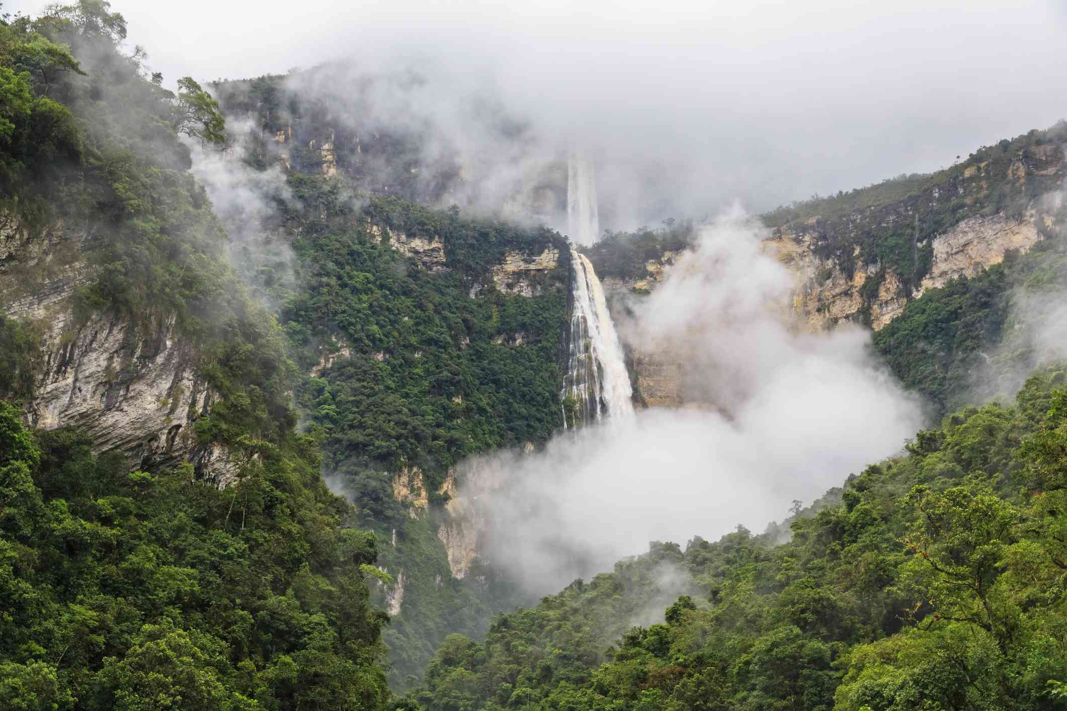 秘鲁的戈塔瀑布，被郁郁葱葱的绿色森林山脉包围，有些被雾挡住了视线＂width=