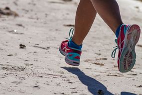 穿着蓝色和粉色运动鞋的人在海滩上跑步