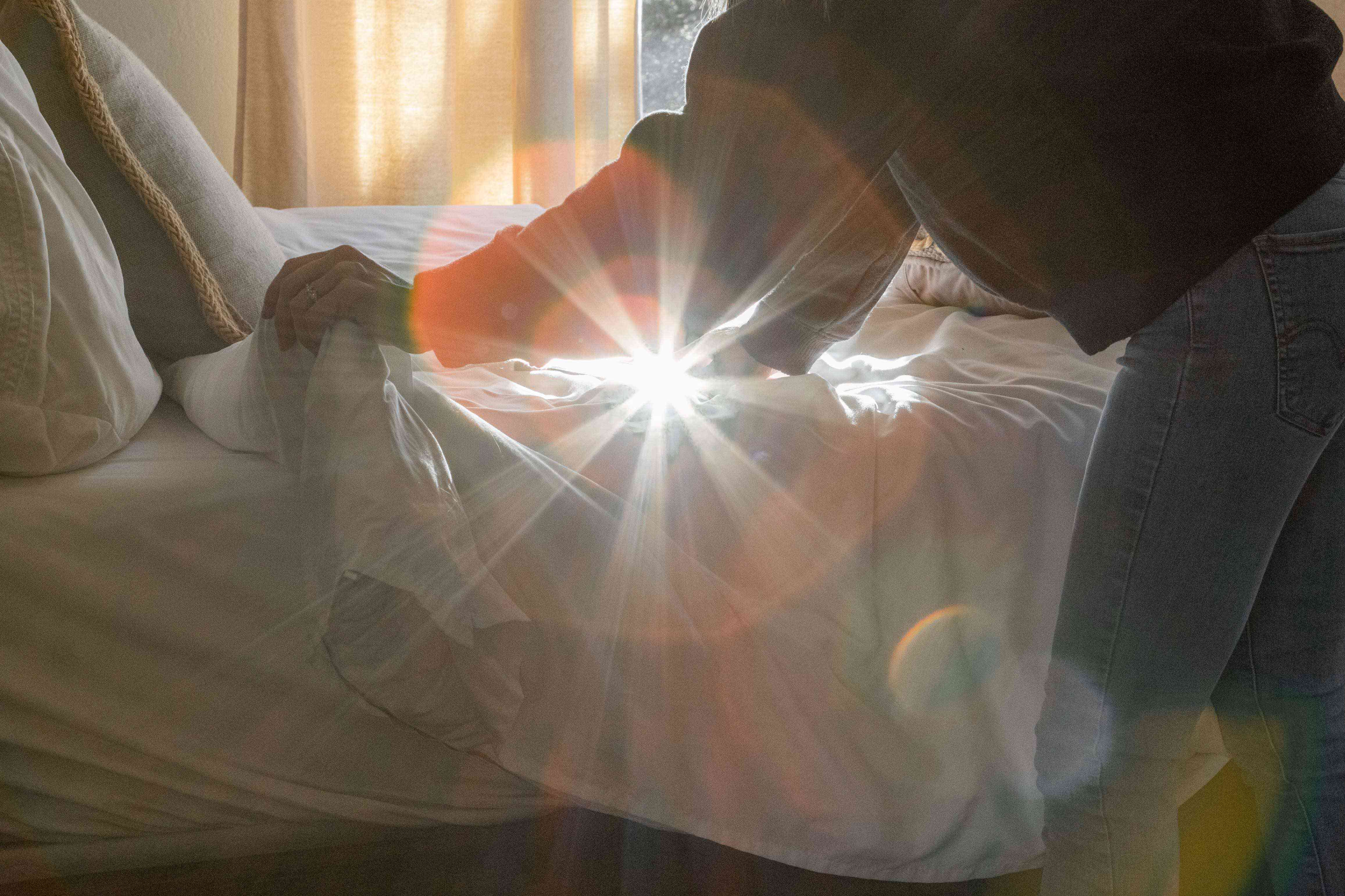 人铺床时，从窗户照进来的阳光在相机上形成了远光灯