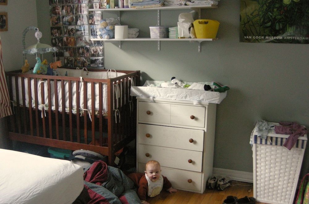 婴儿床，带换尿布垫的梳妆台，卧室角落里放着尿布用品的架子