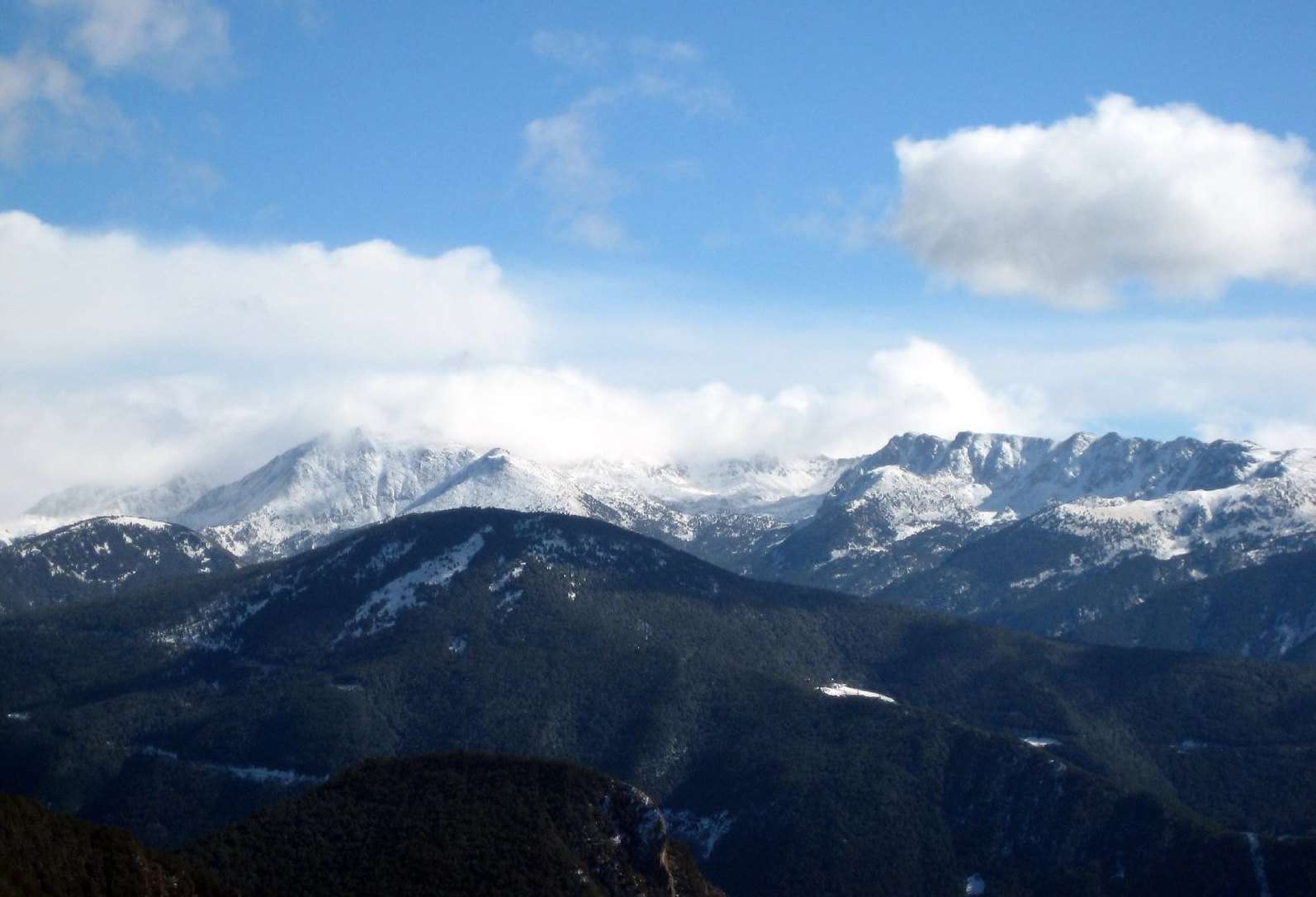 蓝天和几朵云在地平线上的雪山上空盘旋