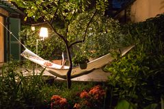 女人在夜晚在郁郁葱葱的花园吊床设置