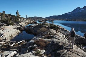 阿罗哈湖旁边的塔霍湖边缘步道上的徒步旅行者＂width=