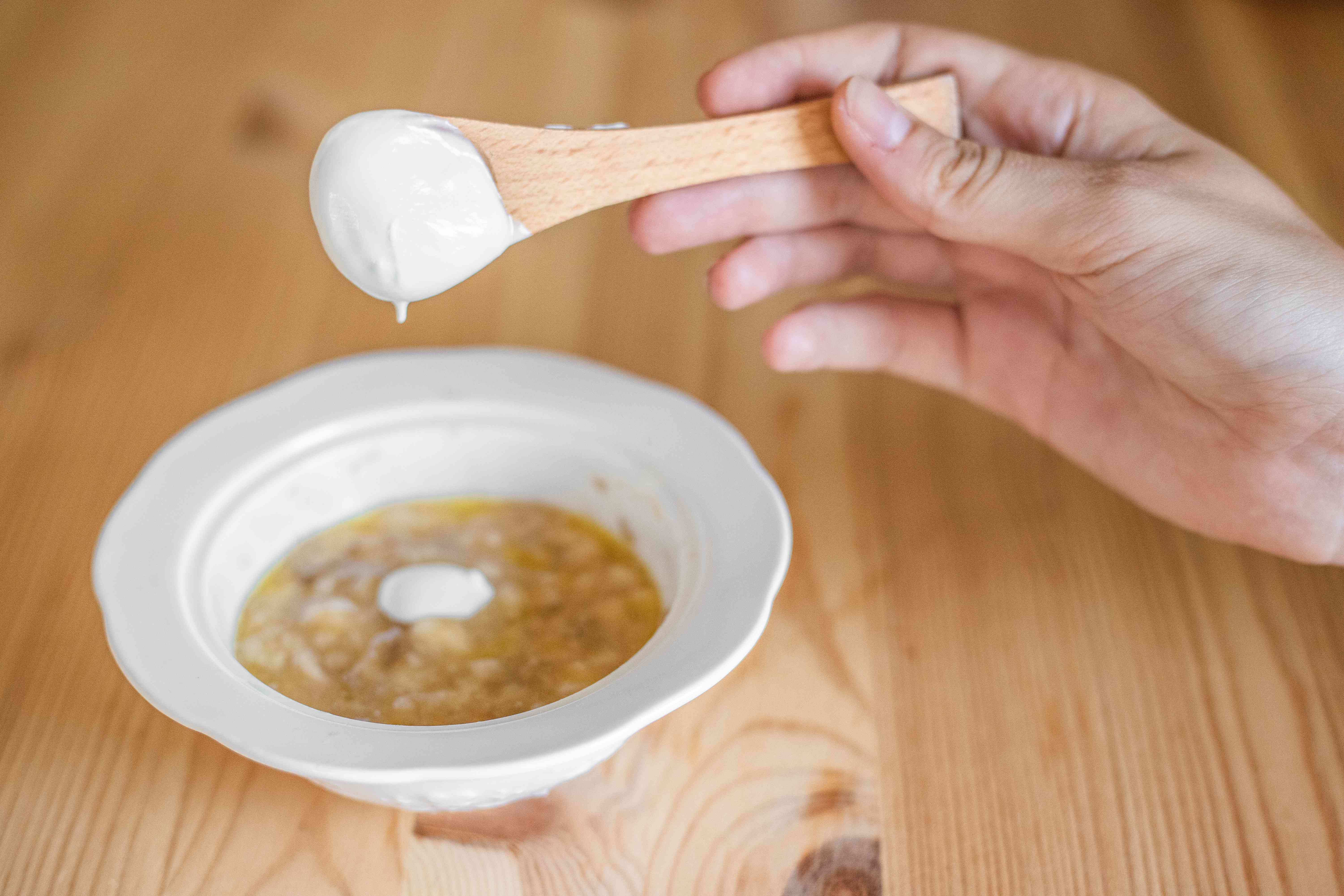 用木勺将浓稠的酸奶加入香蕉泥发膜中