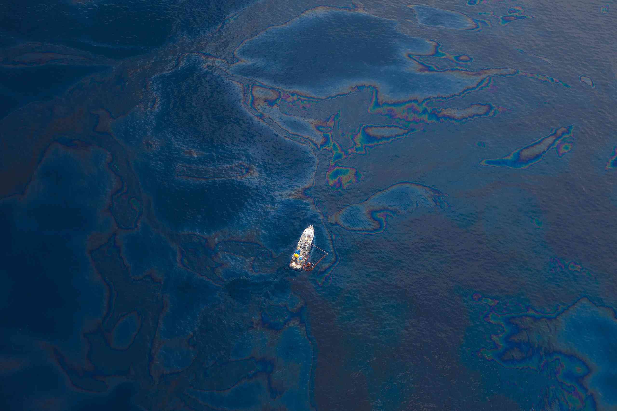 在墨西哥湾的一艘孤船的鸟瞰图，在水面上可见油“width=