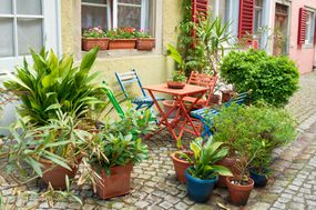 Plants in containers surrounding table outside yellow house