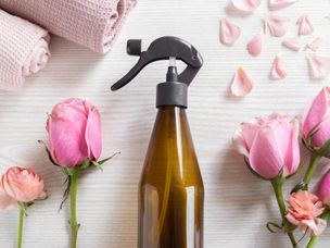 平铺新鲜的粉红色玫瑰和花瓣，可重复使用的棕色玻璃瓶喷雾