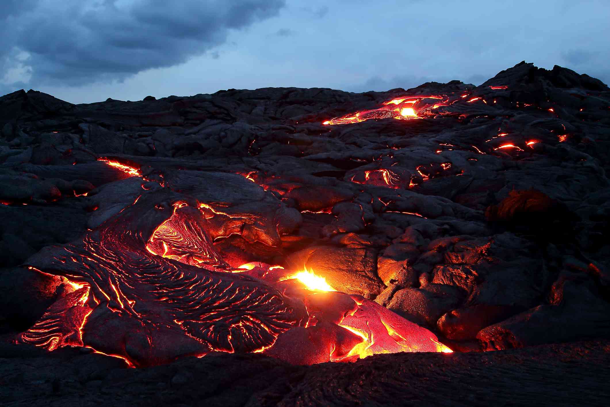 发光的橙色熔岩在深色的火山岩上流动