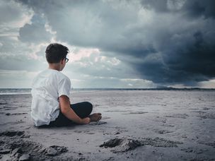 男孩一个人坐在暴风雨的海滩上