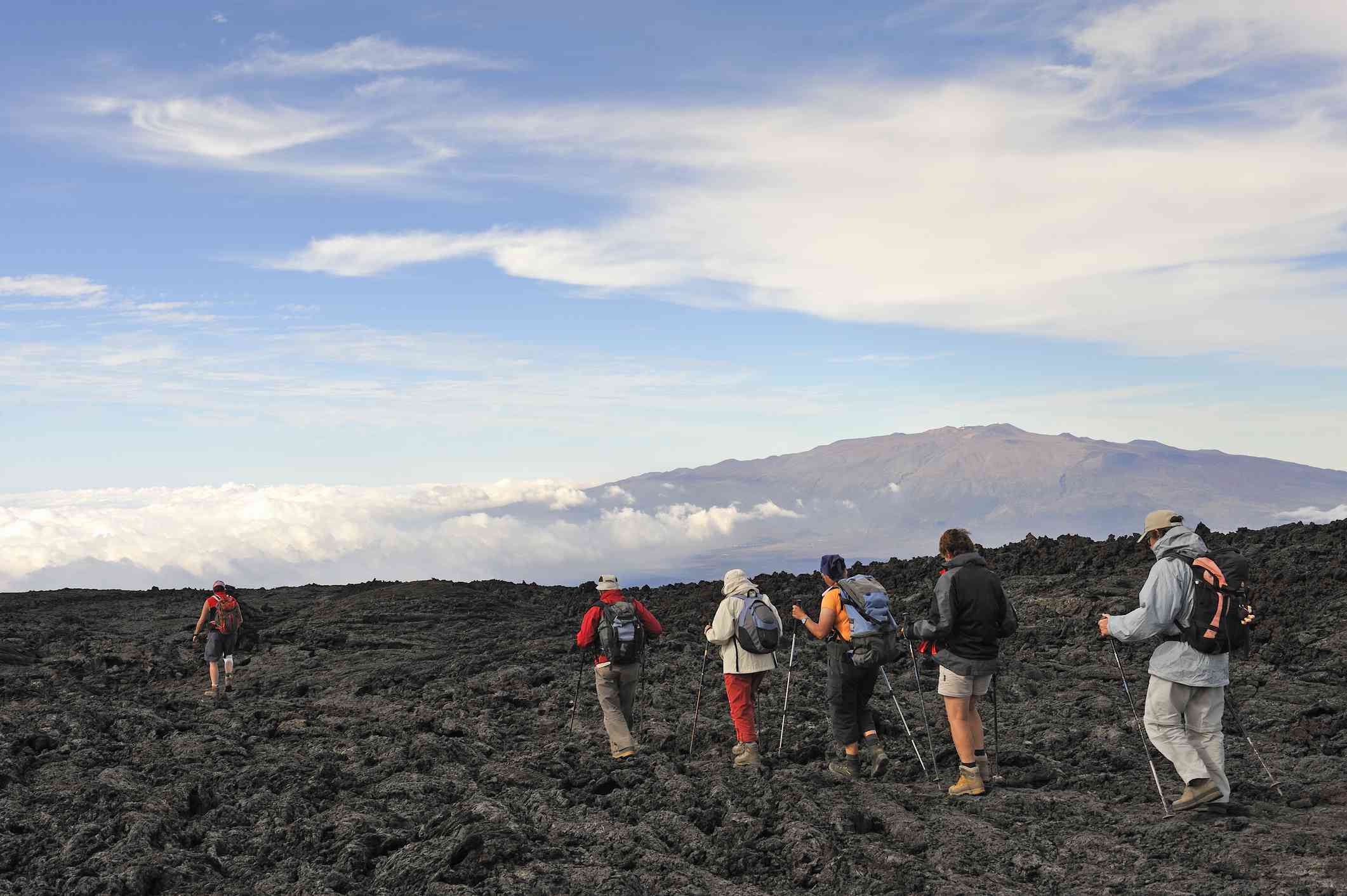 人徒步旅行在熔岩冷却;在后台莫纳罗亚山火山