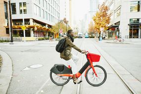 BIPOC一名女子骑着一辆红色电动自行车去市中心上班