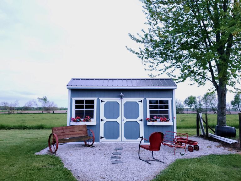 有红色草坪家具的蓝色和白色小房子外面