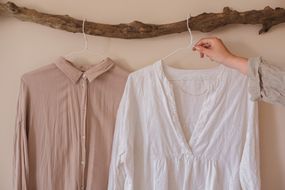 亚麻和棉质衬衫并排挂在升级回收的浮木上＂width=