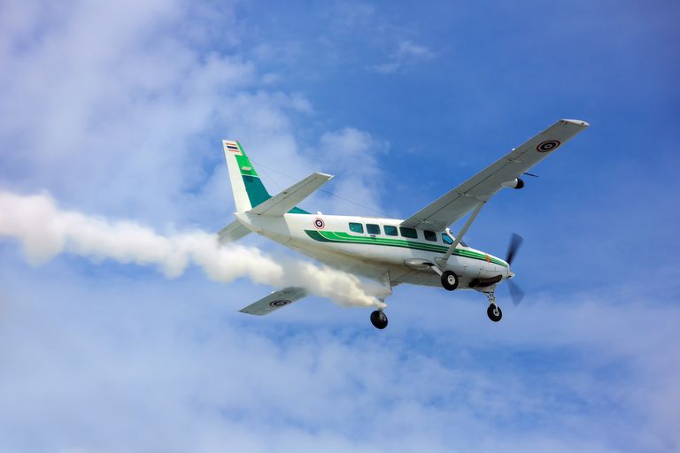 一架涡轮螺旋桨飞机向蓝天中的云层喷洒化学物质的特写镜头。＂class=