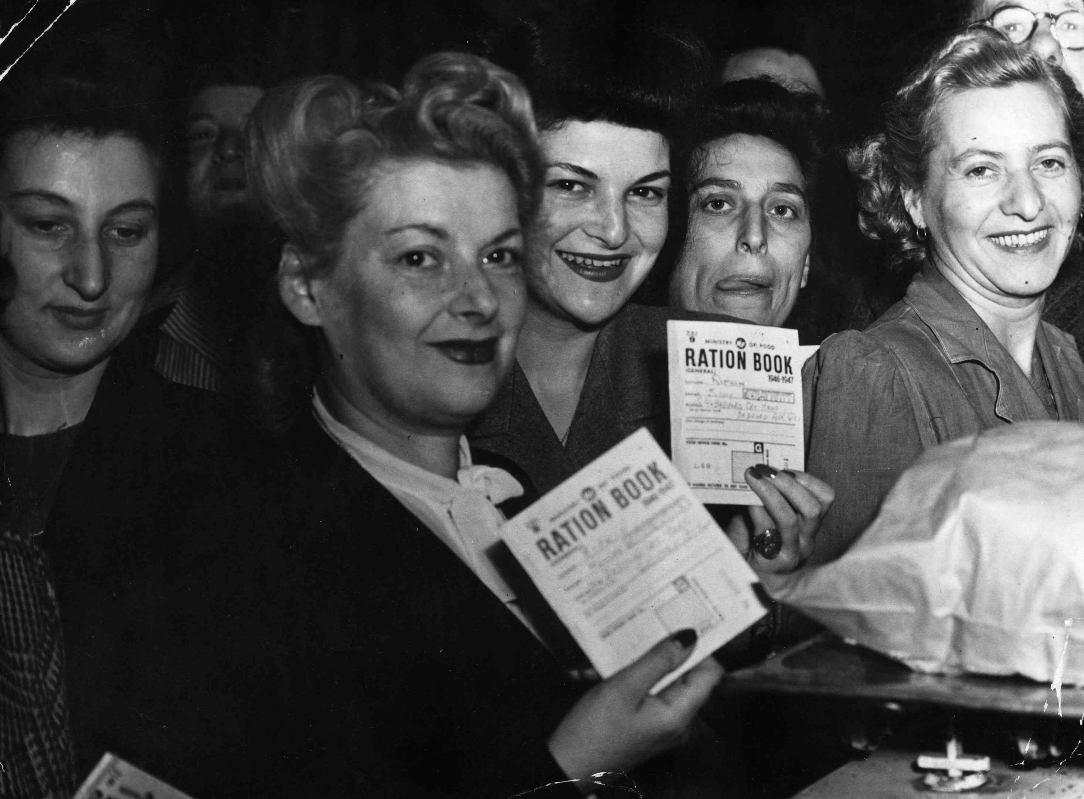 二战期间，面包定量配给的第一天，饥饿的家庭主妇们带着他们的定量配给书来到伦敦的裙巷市场。“width=