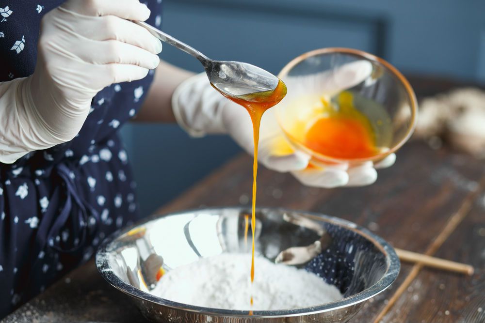 戴手套的女人在碗里搅拌自制的浴弹成分