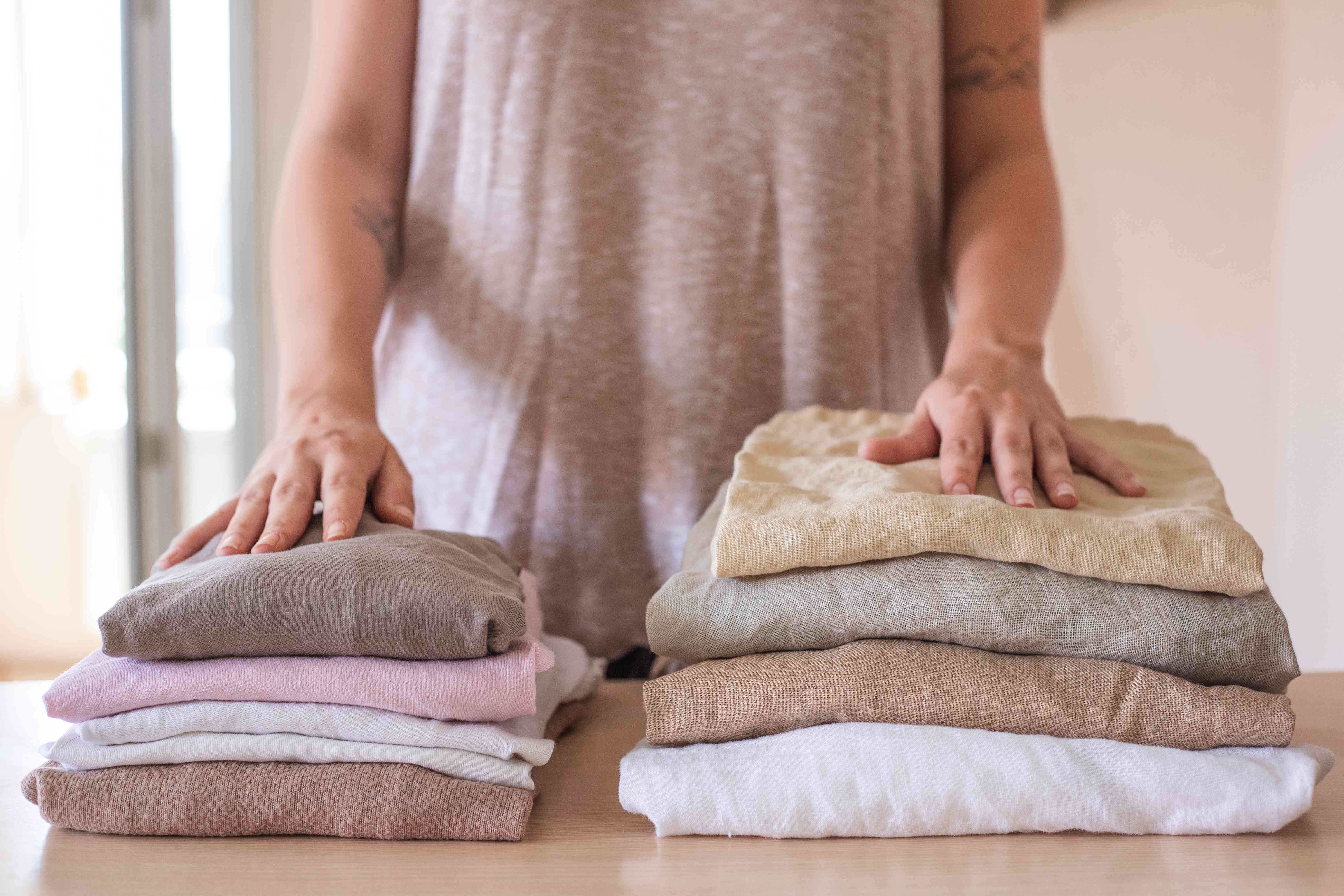 一个人站在两堆叠在一起的衣服前:一件棉的，一件亚麻的＂width=