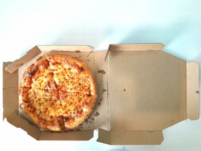 油腻的披萨放在有油渍的纸盒里