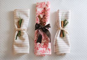三张折叠的餐巾，上面有圣诞装饰和餐巾环