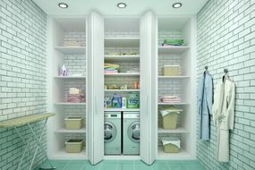白色瓷砖的洗衣房与开放的橱柜显示洗衣机，烘干机，洗衣架上
