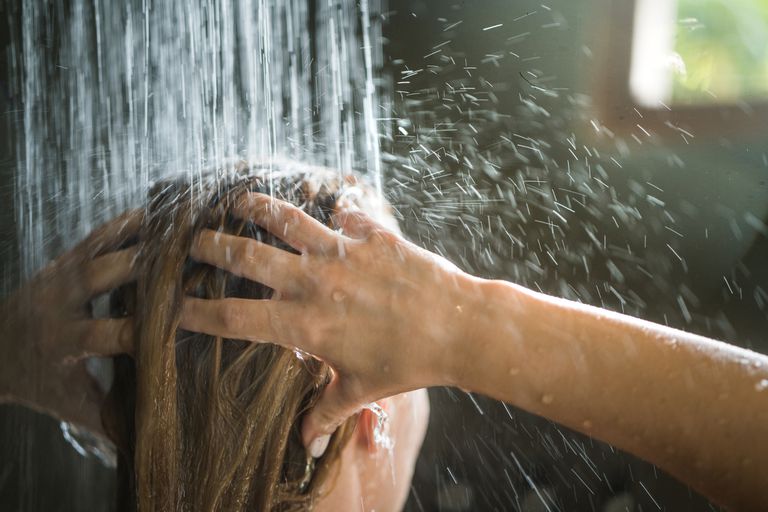 一位妇女在浴室里用自然光洗头。