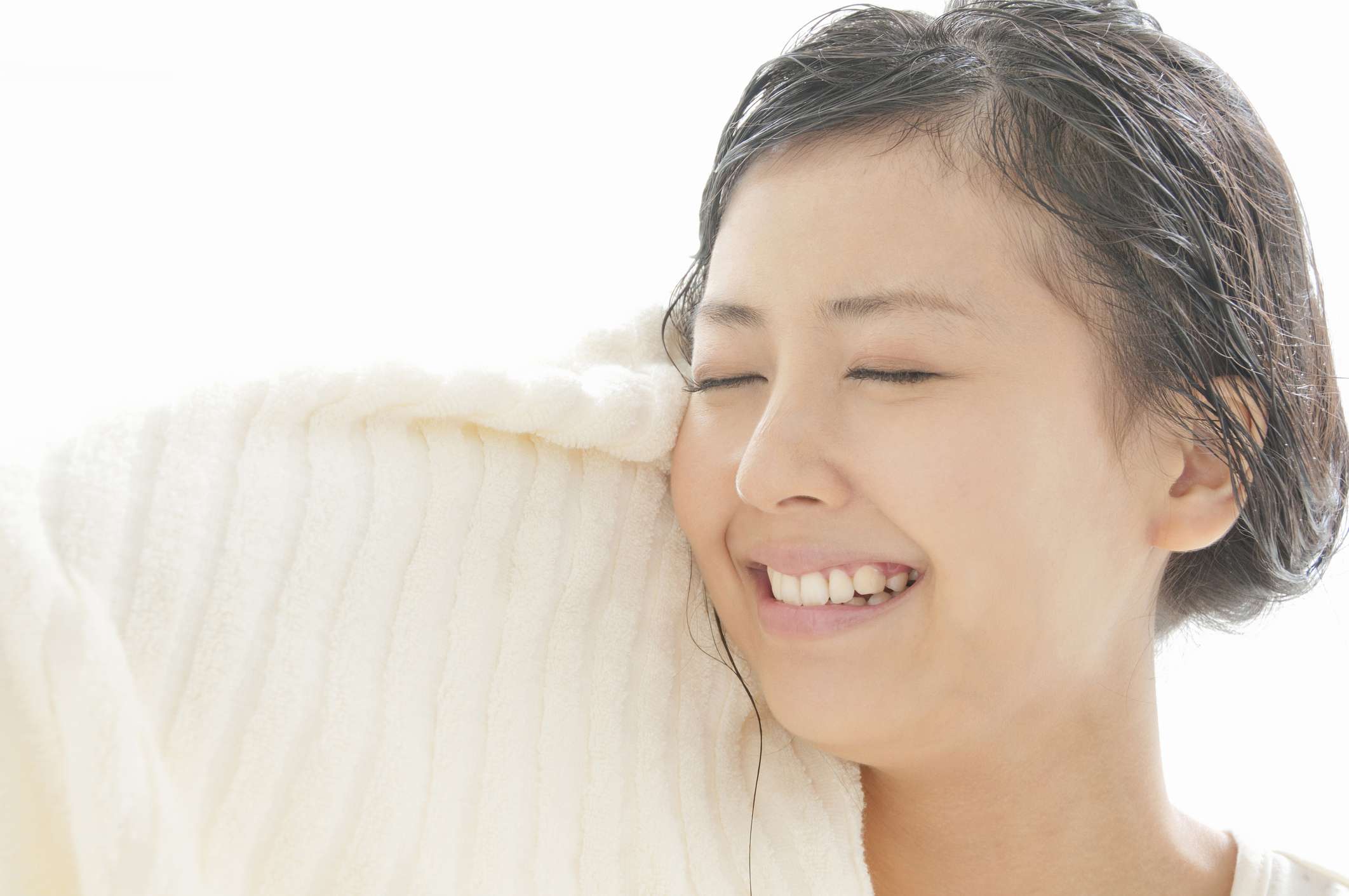 一位亚洲妇女用毛巾擦干她的湿头发。
