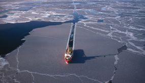 在一个阳光明媚的日子，一艘船在北极的海冰上开道。