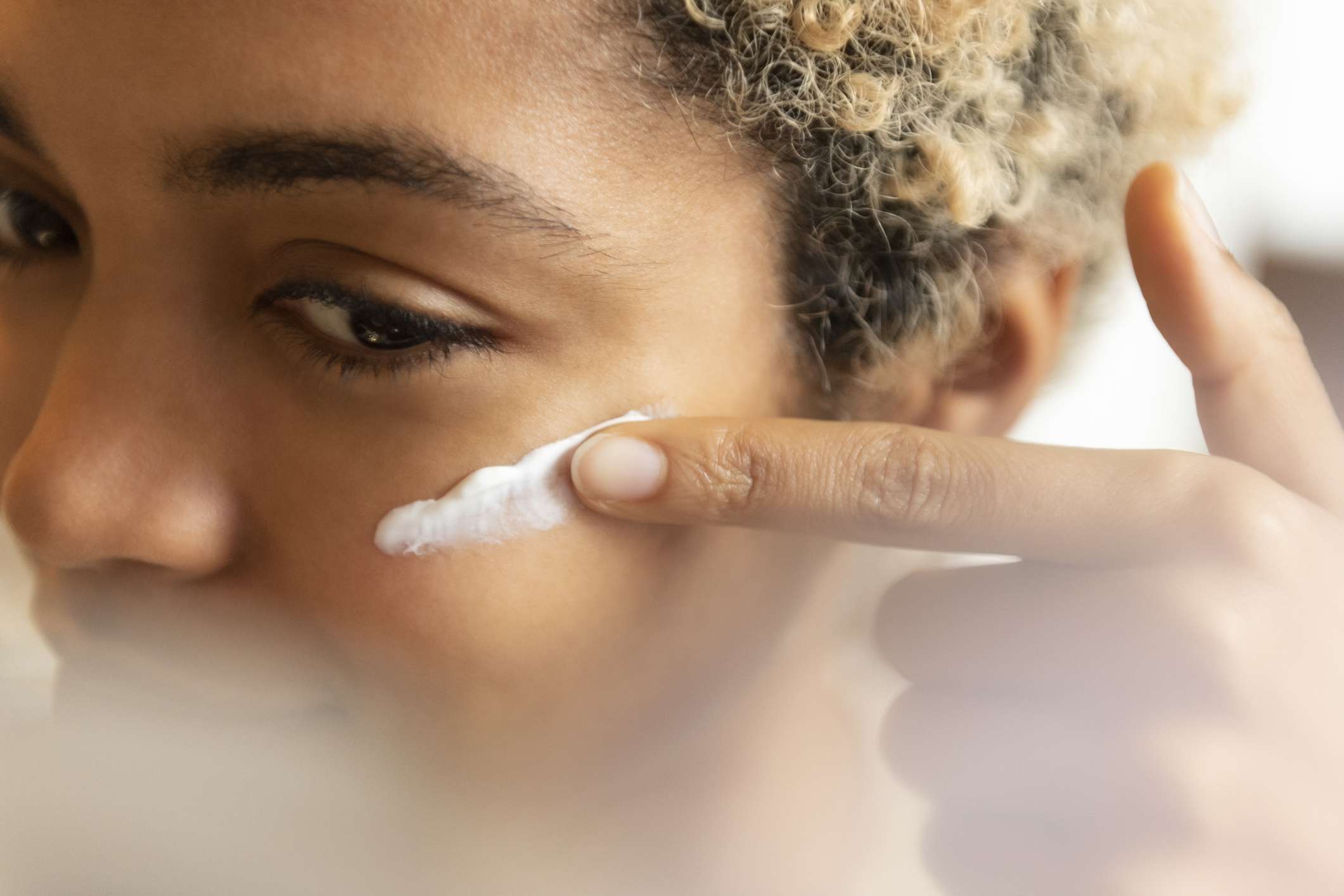 一名黑人妇女在脸上涂保湿霜。
