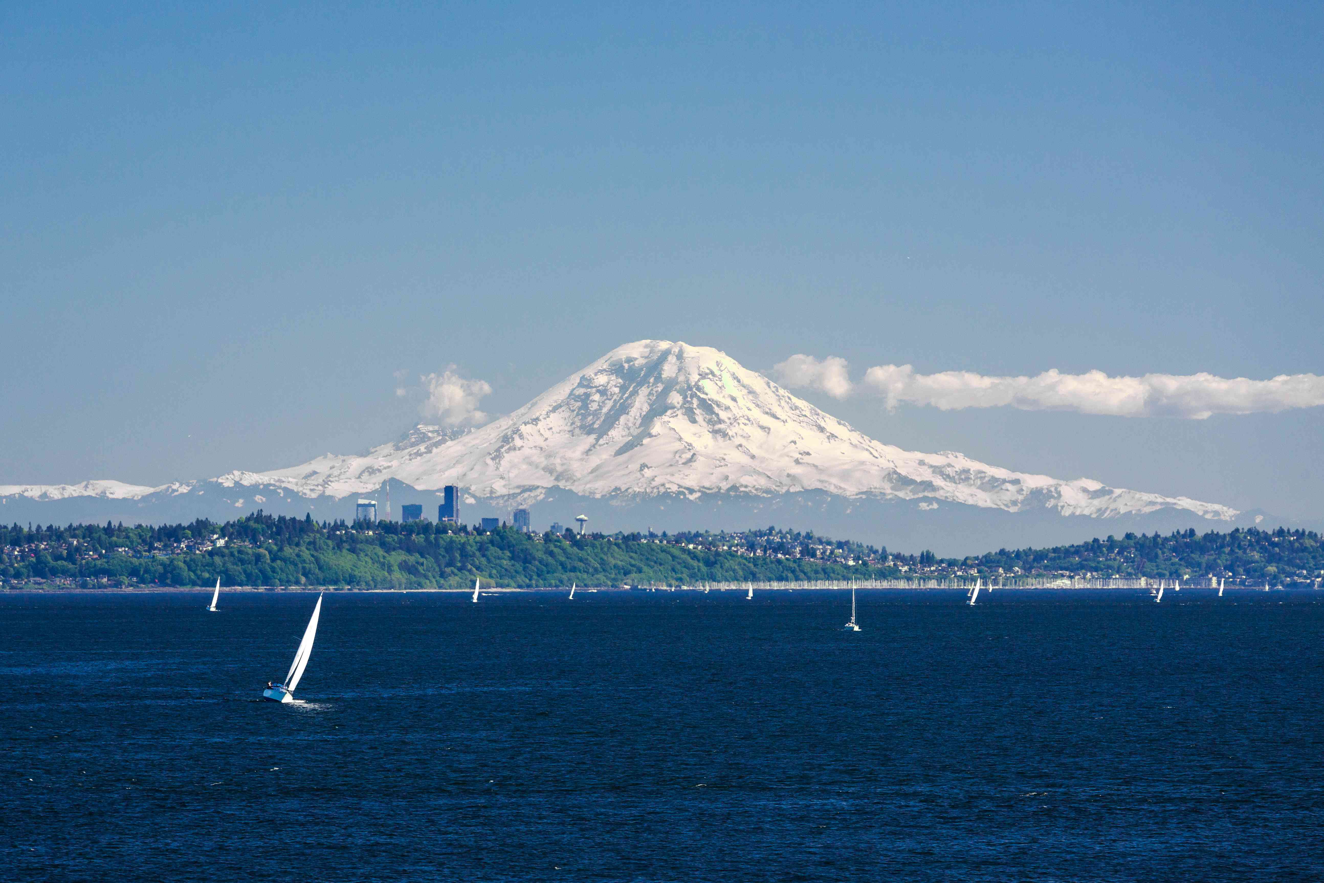 雷尼尔山（Mount Rainier）在华盛顿州阳光明媚的日子耸立在西雅图，普吉特海湾和帆船“width=