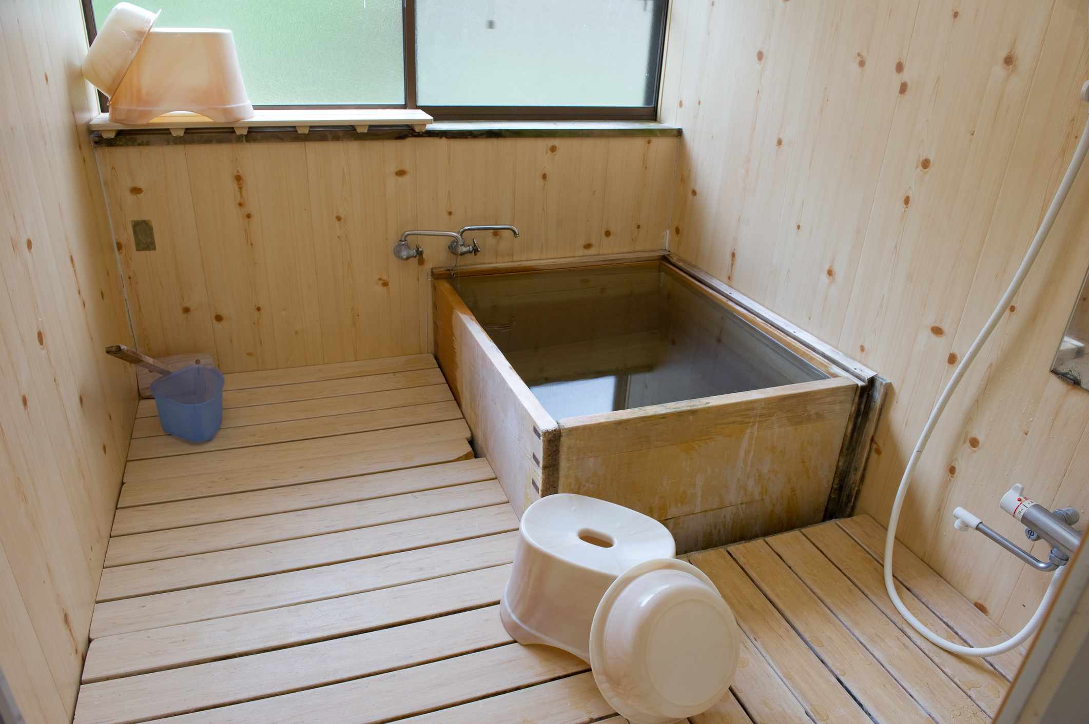 一间日本的木制盥洗室，有浴盆和凳子，用来洗澡的桶。