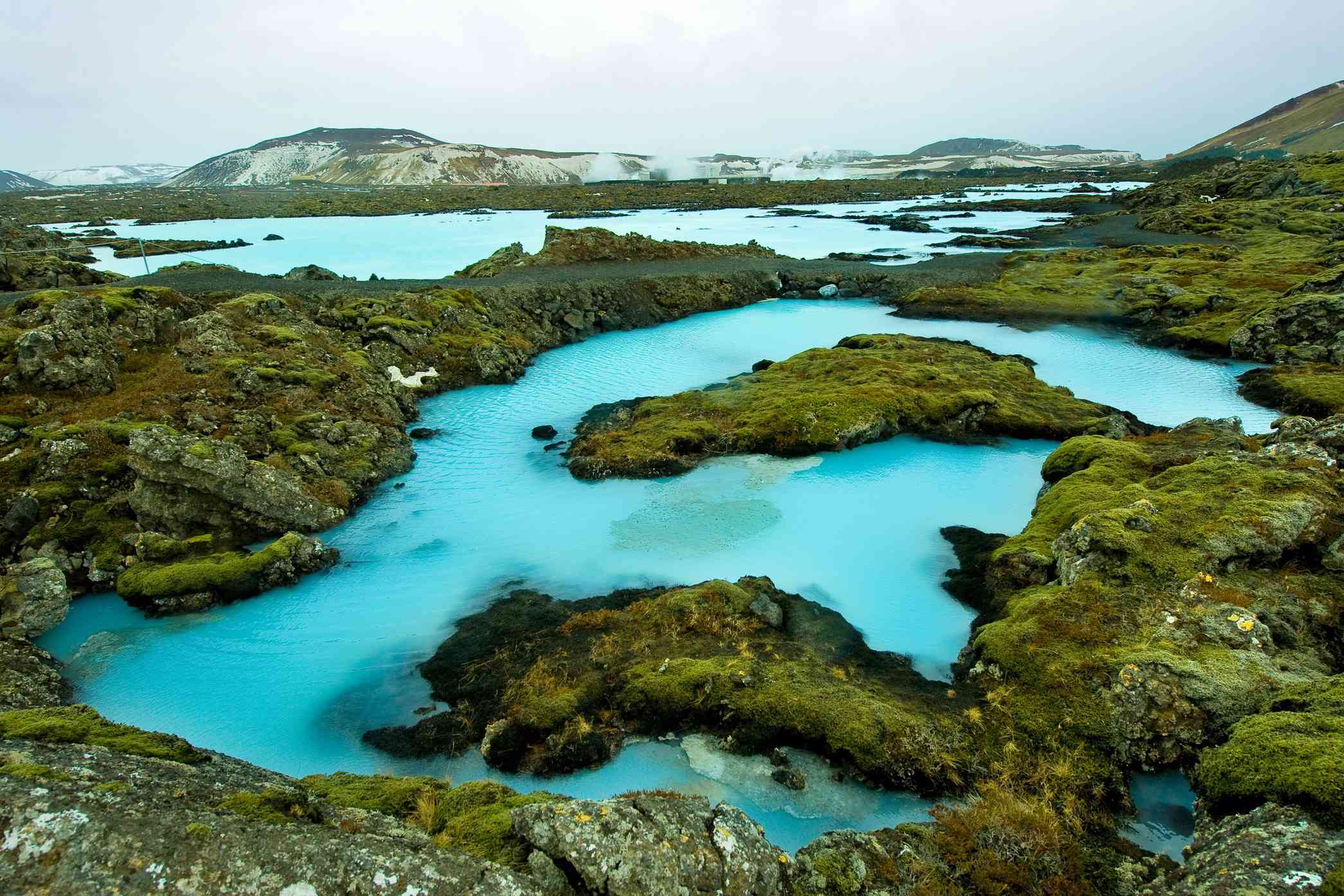 青苔覆盖的熔岩石之间流淌着蓝色的水