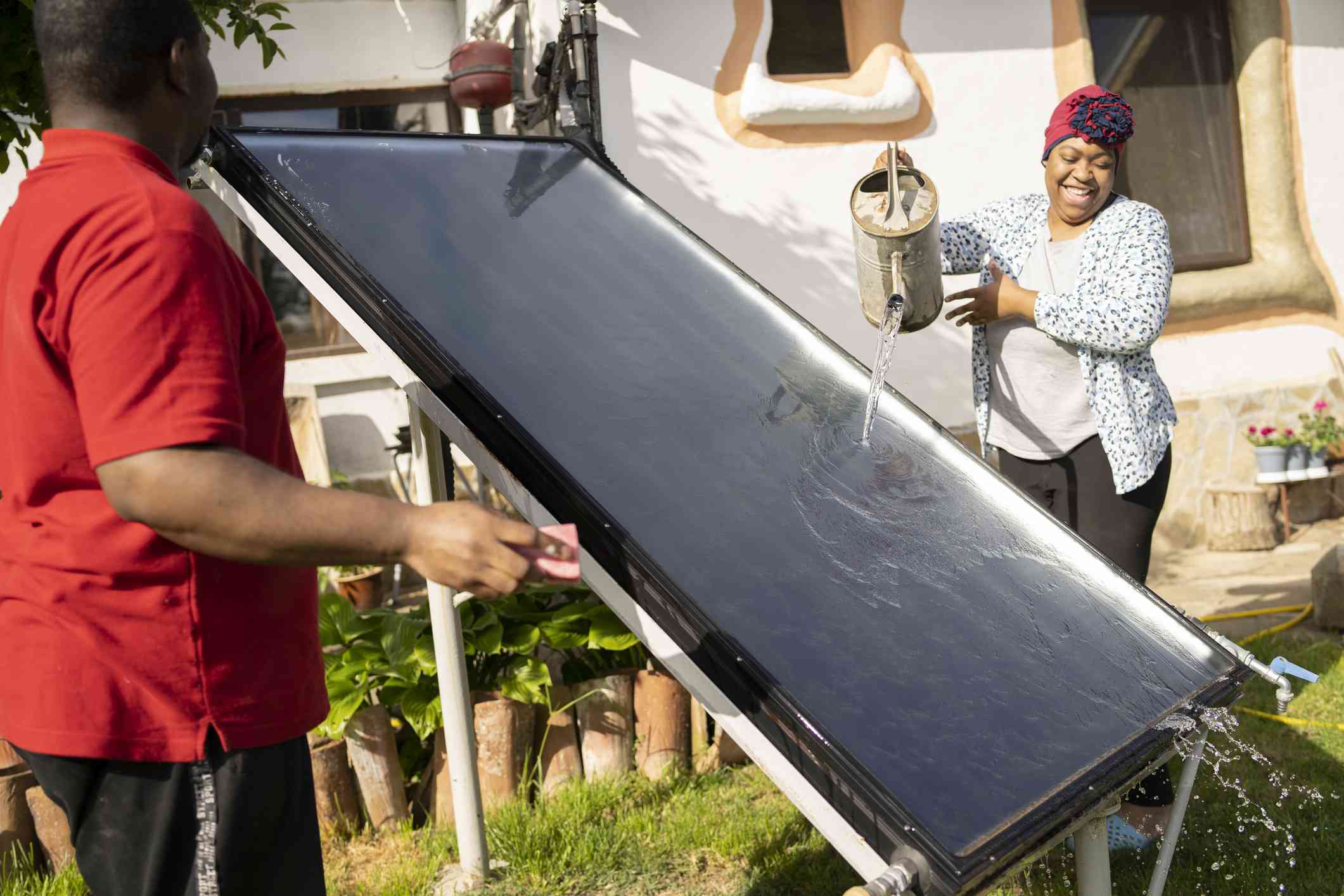 夫妇清洁太阳能电池板与喷壶＂width=