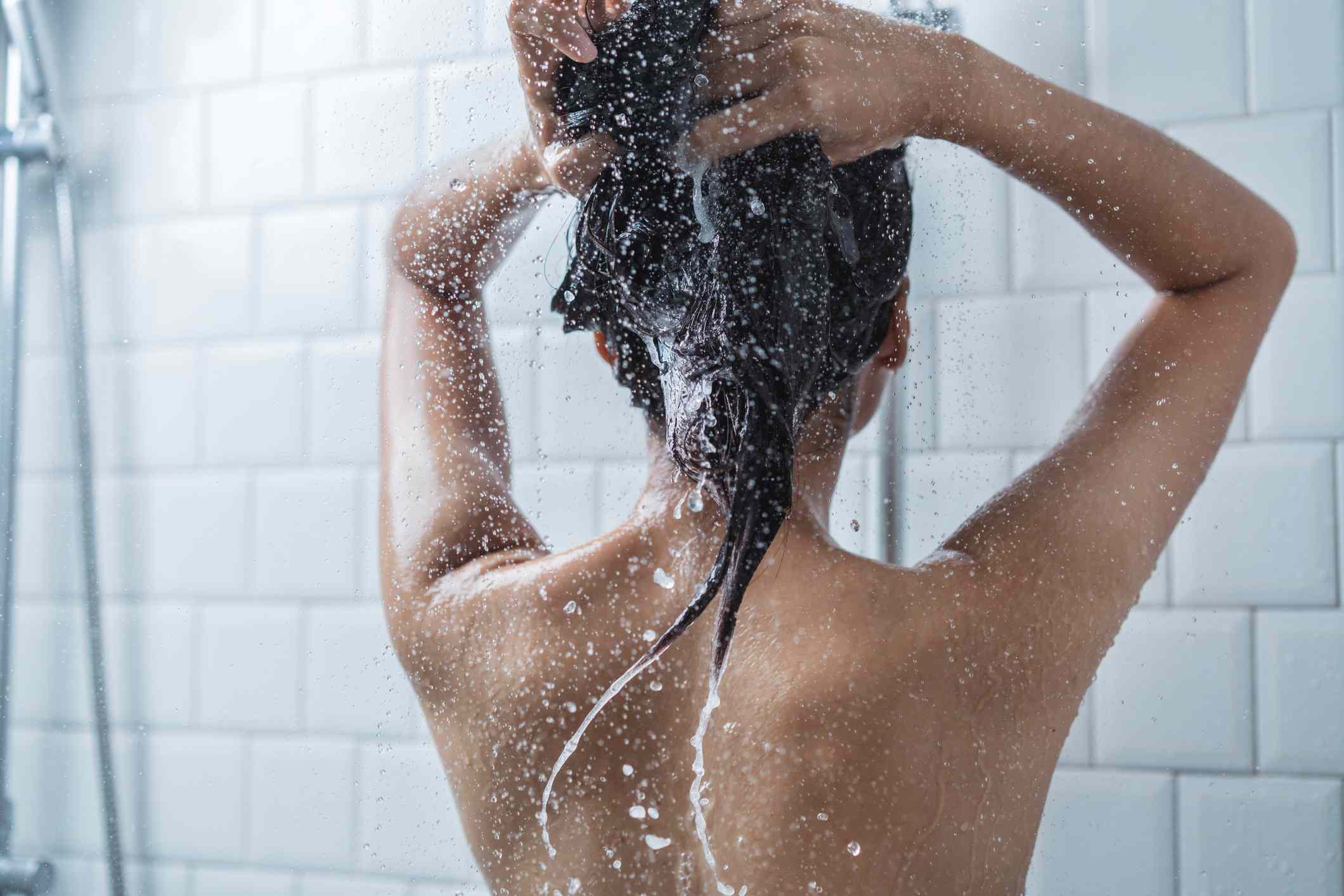 一个女人用白色的淋浴洗头。
