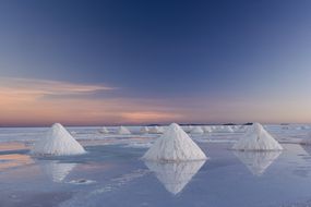 乌尤尼盐滩上三角形的盐堆，倒映着日出