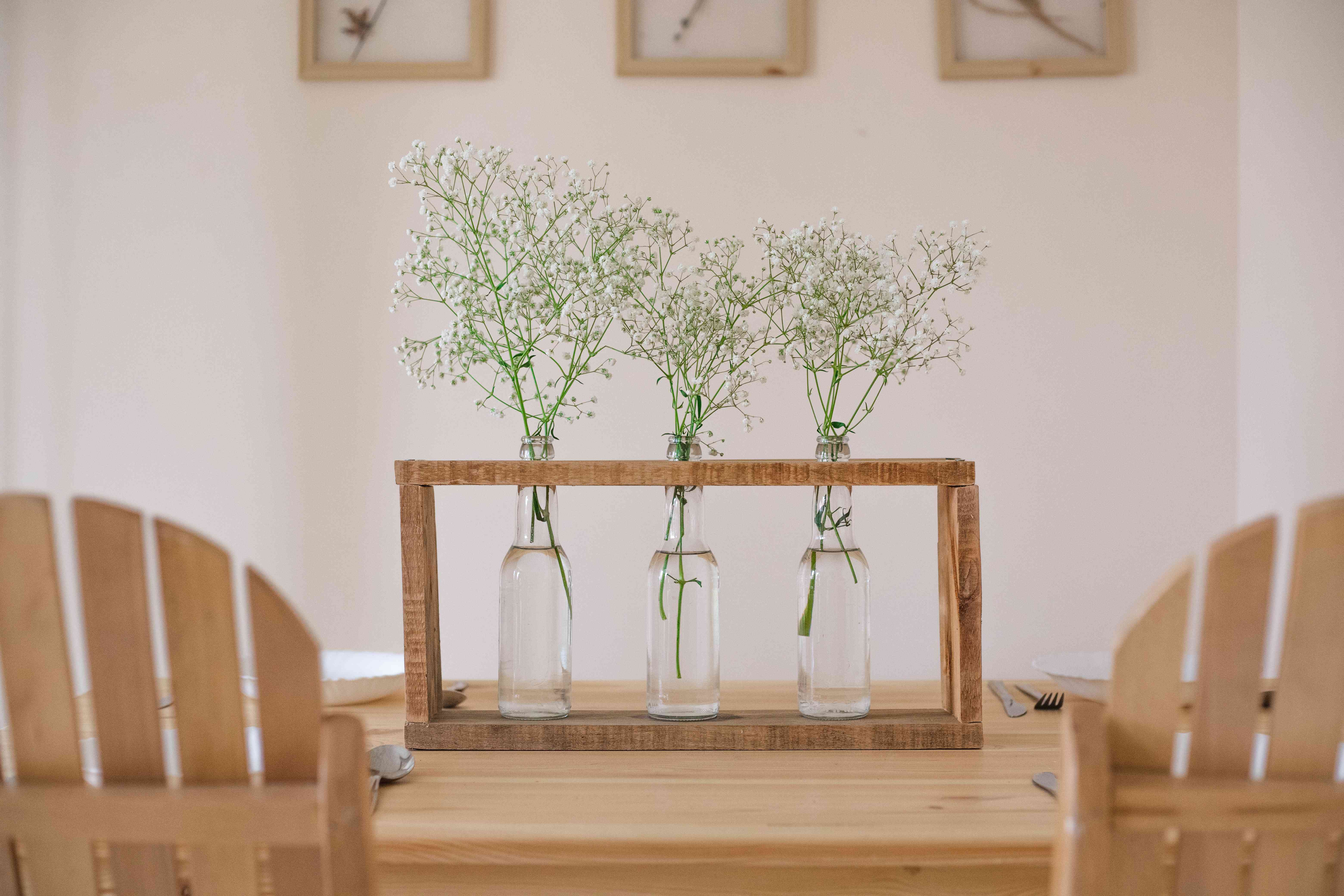 升级回收的玻璃瓶作为现代木花瓶中心与鲜花在木桌上