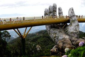 在越南岘港附近，金色的Cau Vang桥似乎由一只大石手支撑着