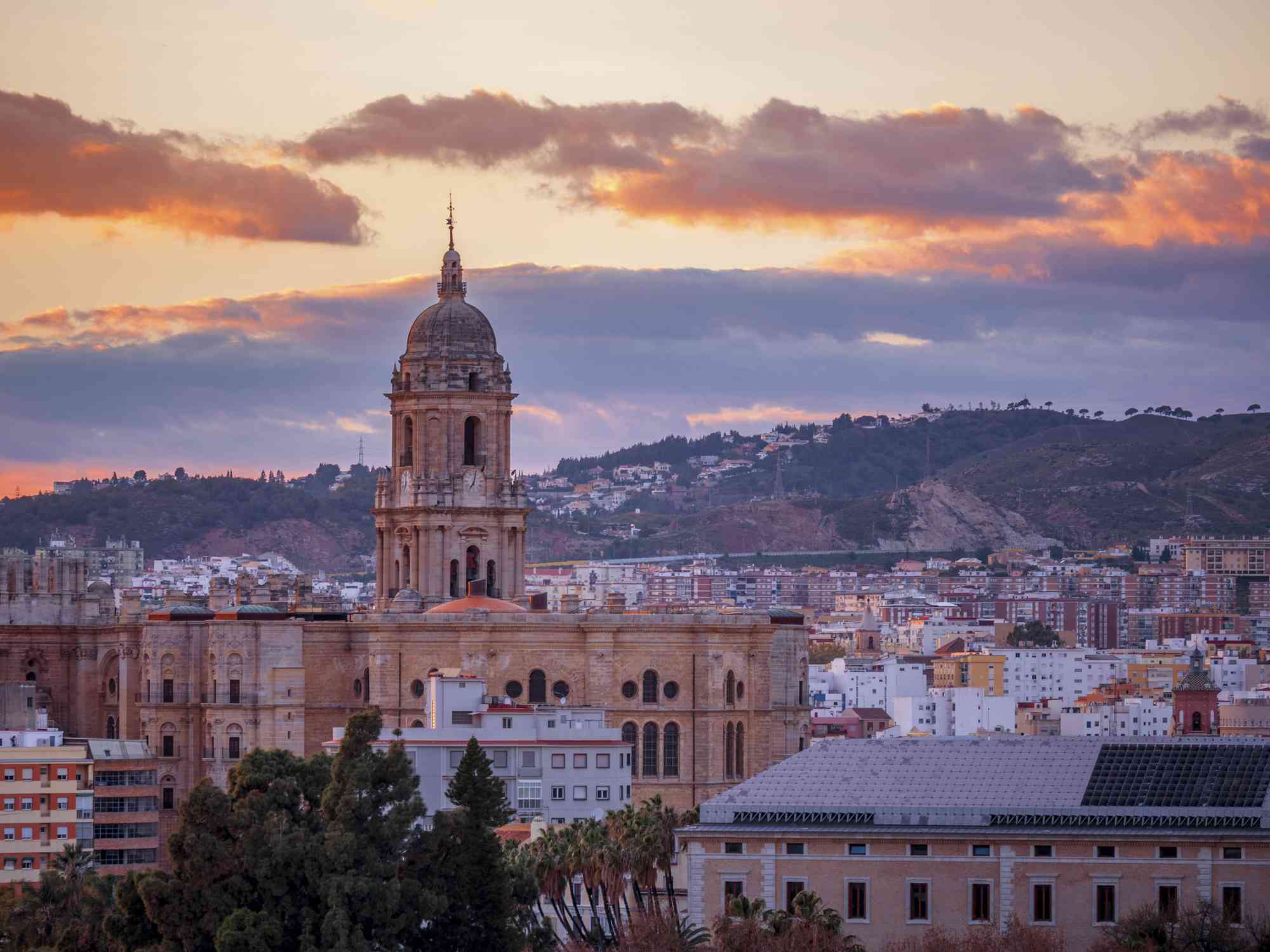 太阳开始落山时，西班牙马拉加大教堂的圆顶从城市上空升起
