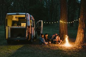 朋友们围坐在露营车旁的篝火旁